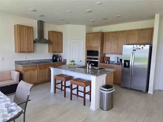 1764 Stamen Dr, Kissimmee, FL 34744 - kitchen featuring wall chimney exhaust hood, appliances with stainless steel finishes, an island with sink, dark stone counters, and a breakfast bar area