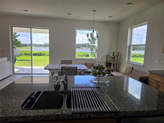 1764 Stamen Dr, Kissimmee, FL 34744 - kitchen with a water view, hanging light fixtures, a notable chandelier, and dark stone counters