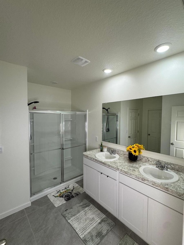 7162 Tigereye Way, Grant, FL 32949 - bathroom with double vanity, a shower stall, a textured ceiling, tile patterned flooring, and recessed lighting
