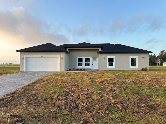 view of front of house with a front yard, an attached garage, decorative driveway, and stucco siding