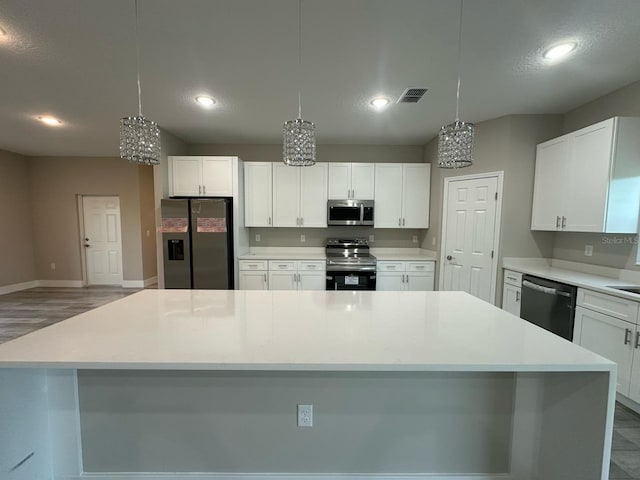 kitchen featuring a notable chandelier, white cabinets, visible vents, a spacious island, and appliances with stainless steel finishes