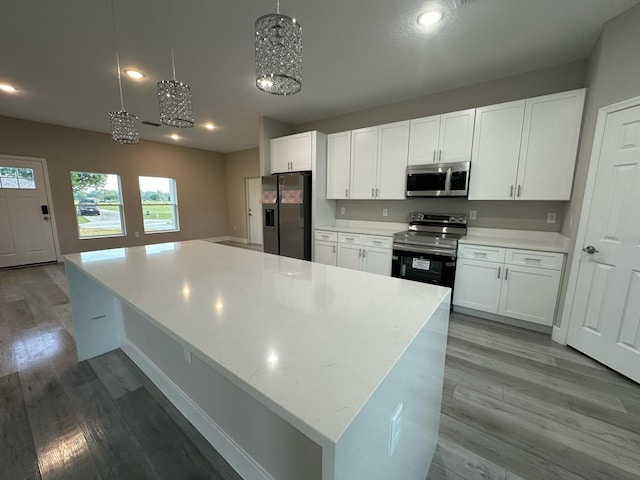 kitchen with white cabinets, wood finished floors, and appliances with stainless steel finishes