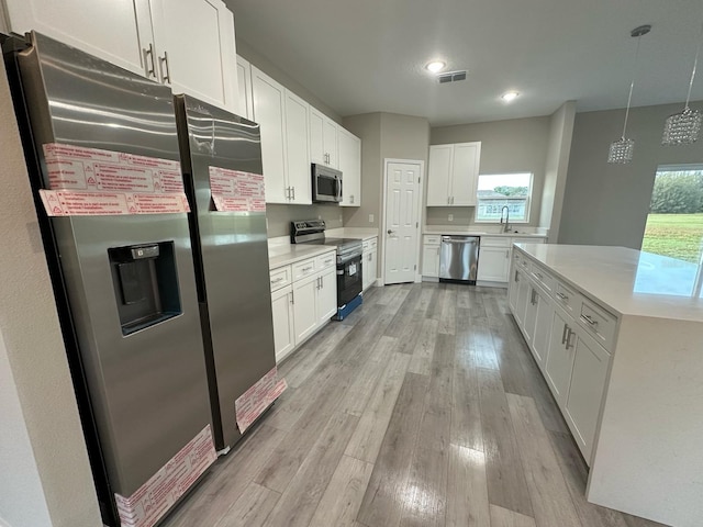kitchen featuring visible vents, light countertops, light wood-type flooring, appliances with stainless steel finishes, and white cabinetry