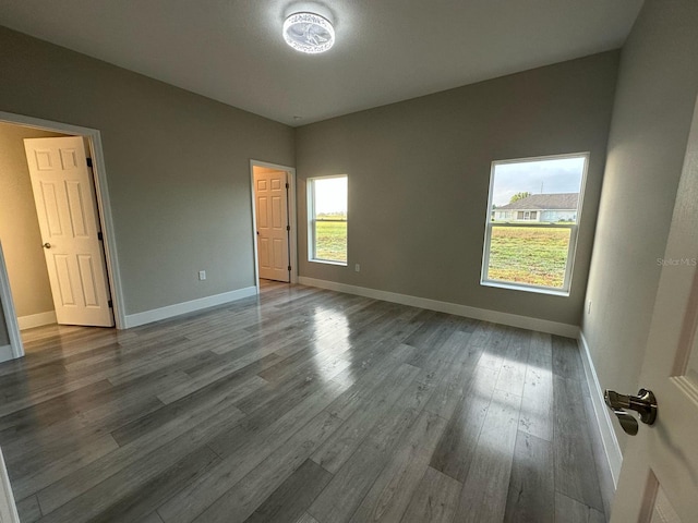 unfurnished bedroom with dark wood-type flooring and baseboards