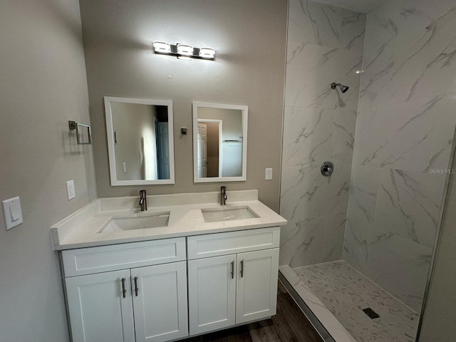 full bath featuring double vanity, a marble finish shower, and a sink