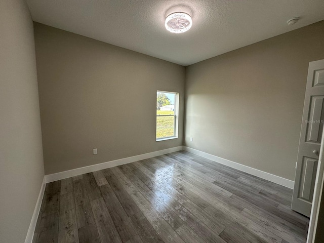 empty room featuring baseboards, a textured ceiling, and wood finished floors