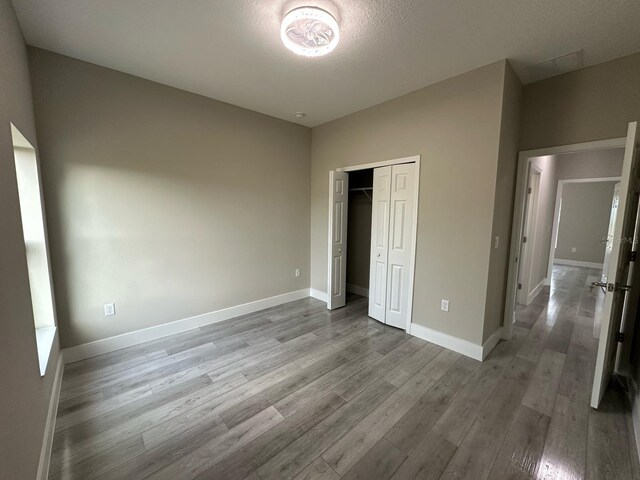 unfurnished bedroom with a closet, baseboards, and wood finished floors