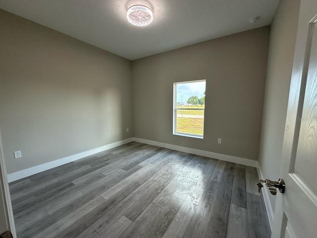 unfurnished room with baseboards and wood finished floors