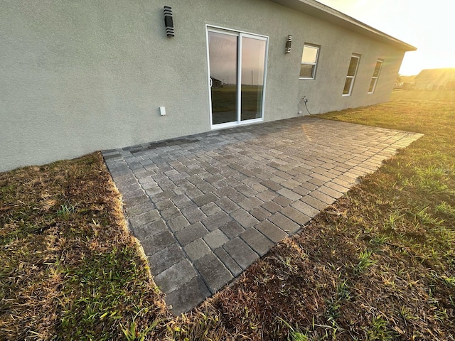 back of house featuring a patio area, stucco siding, and a lawn