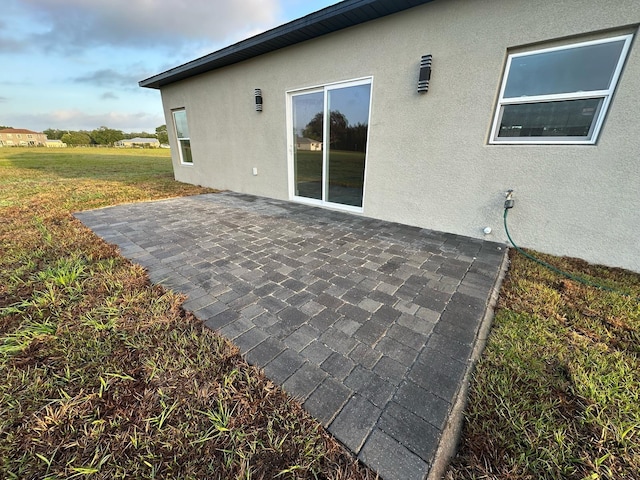 back of house with a patio, stucco siding, and a lawn