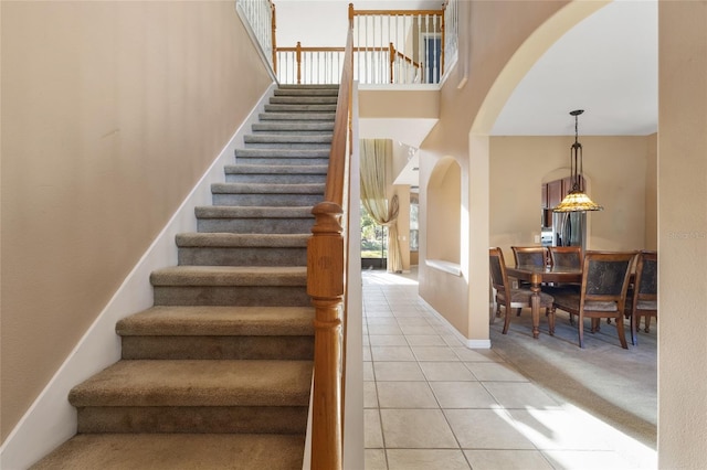 9244 Pecky Cypress Way, Orlando, FL 32836 - stairway with arched walkways, tile patterned flooring, baseboards, a high ceiling, and carpet flooring