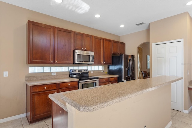 9244 Pecky Cypress Way, Orlando, FL 32836 - kitchen with stainless steel appliances, arched walkways, visible vents, and light tile patterned floors