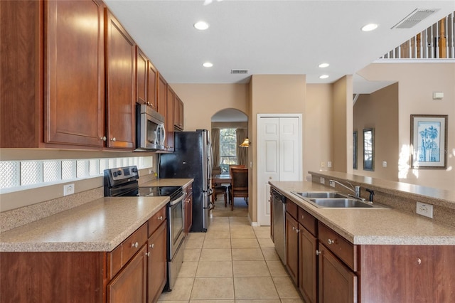 9244 Pecky Cypress Way, Orlando, FL 32836 - kitchen featuring visible vents, arched walkways, a sink, light tile patterned floors, and stainless steel appliances
