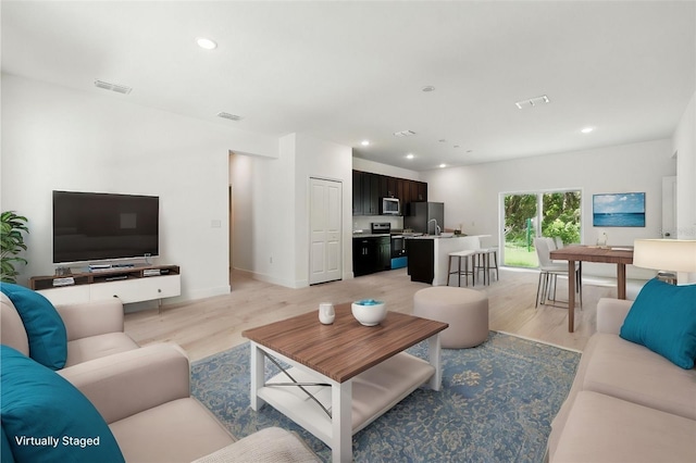 living area with light wood finished floors, recessed lighting, and baseboards