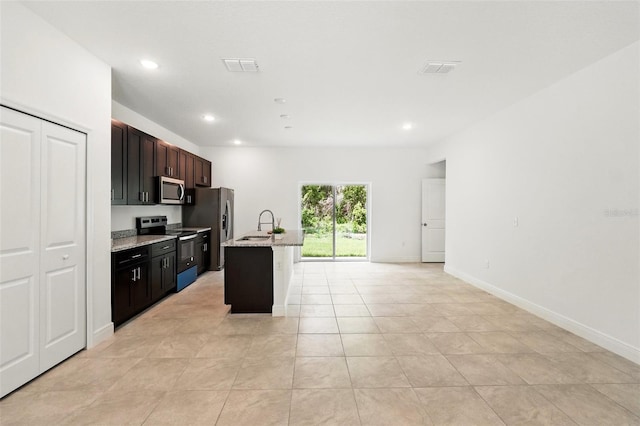 kitchen featuring stainless steel appliances, a sink, light tile patterned flooring, an island with sink, and recessed lighting