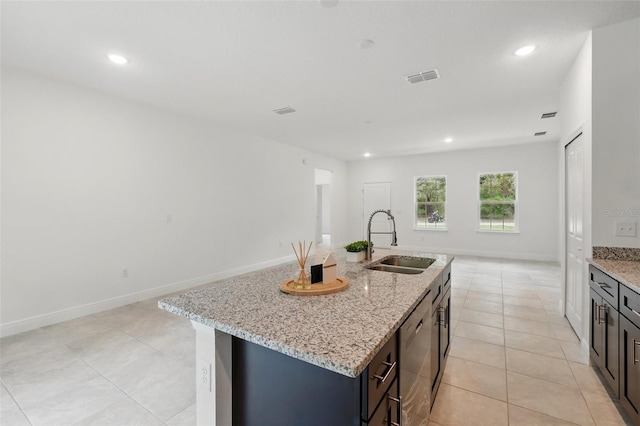 kitchen with a sink, stainless steel dishwasher, light tile patterned floors, recessed lighting, and light stone counters