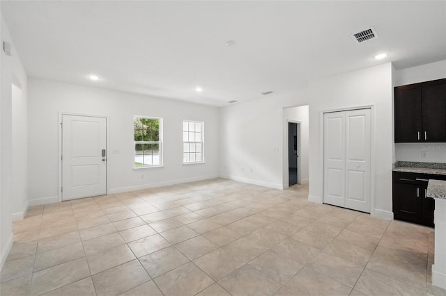 unfurnished living room featuring light tile patterned flooring, recessed lighting, and baseboards