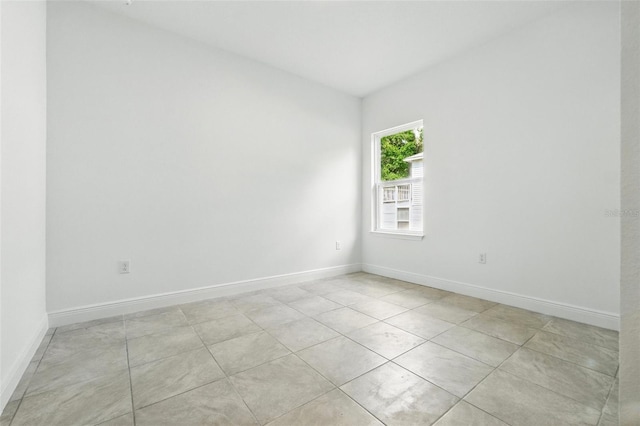 spare room with baseboards and light tile patterned floors