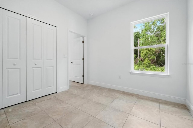 unfurnished bedroom with baseboards, light tile patterned floors, and a closet