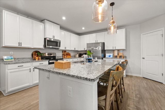 4301 Creek Bank Dr, Kissimmee, FL 34744 - kitchen with a center island with sink, appliances with stainless steel finishes, light wood finished floors, and white cabinets