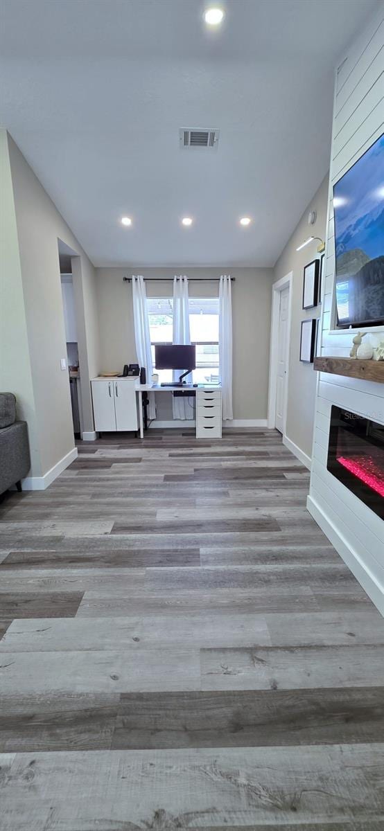unfurnished living room with baseboards, wood finished floors, visible vents, and a large fireplace