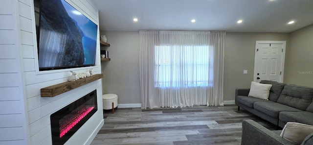 living room with a fireplace, wood finished floors, baseboards, and recessed lighting