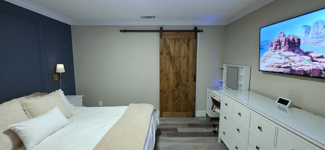 bedroom featuring a barn door, light wood-style floors, visible vents, and ornamental molding