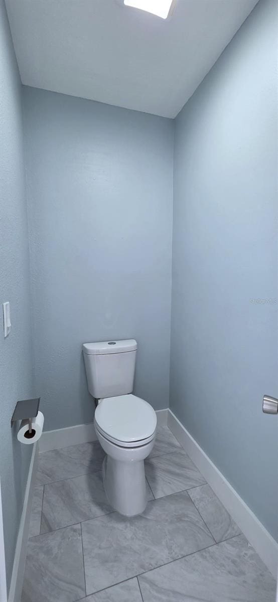 bathroom with marble finish floor, baseboards, and toilet