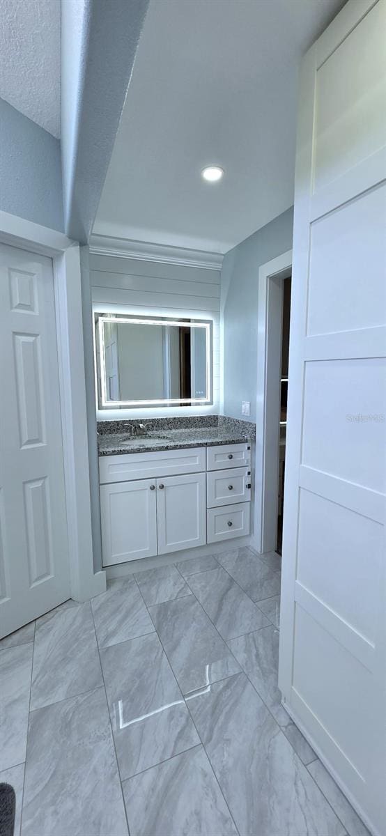 hallway featuring marble finish floor, a sink, and recessed lighting