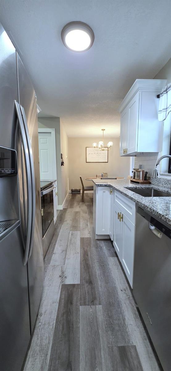 kitchen with dark wood-style flooring, white cabinetry, a chandelier, and stainless steel appliances