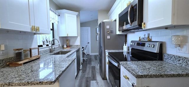 kitchen featuring a sink, light wood-type flooring, tasteful backsplash, appliances with stainless steel finishes, and white cabinetry