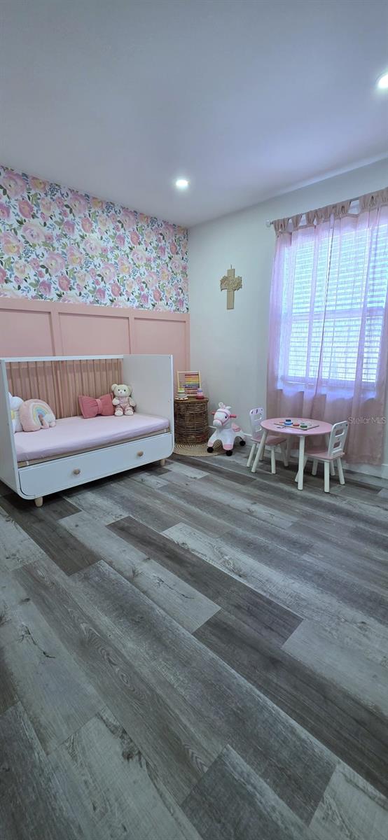 bedroom with wallpapered walls, wood finished floors, and recessed lighting