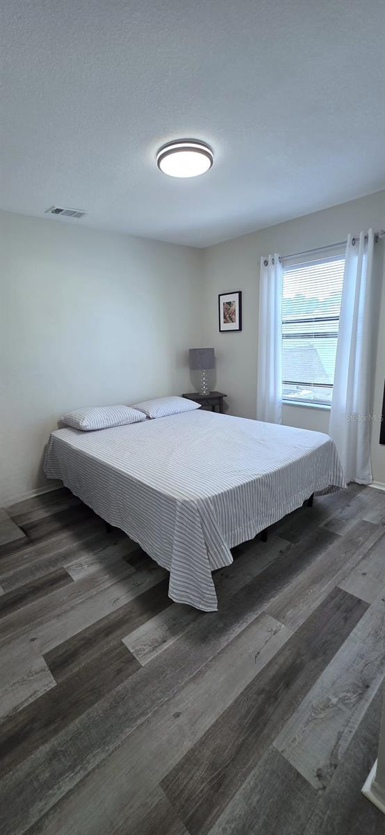 bedroom featuring wood finished floors and visible vents