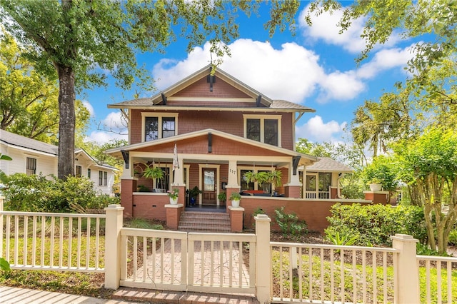 view of front facade with covered porch, a shingled roof, a gate, and a fenced front yard