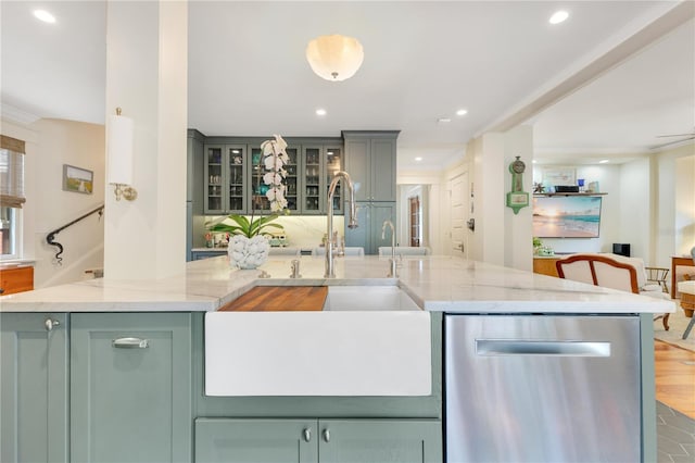 kitchen with light stone countertops, dishwasher, recessed lighting, and a sink