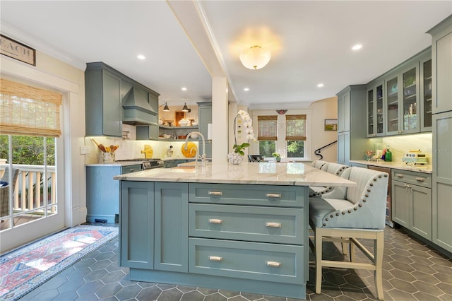 kitchen with a kitchen island with sink, light stone countertops, tasteful backsplash, and a healthy amount of sunlight