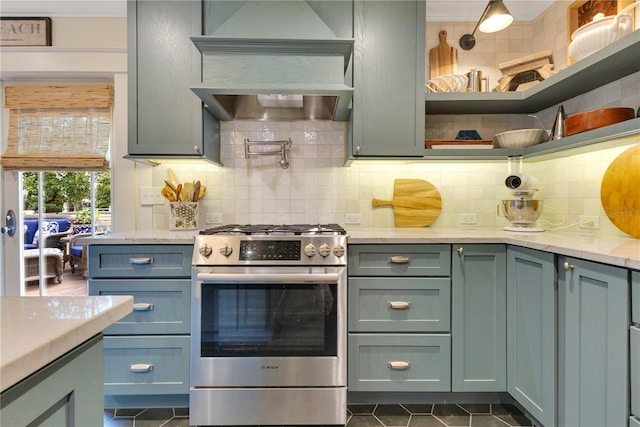 kitchen with dark tile patterned floors, stainless steel range with gas cooktop, and decorative backsplash