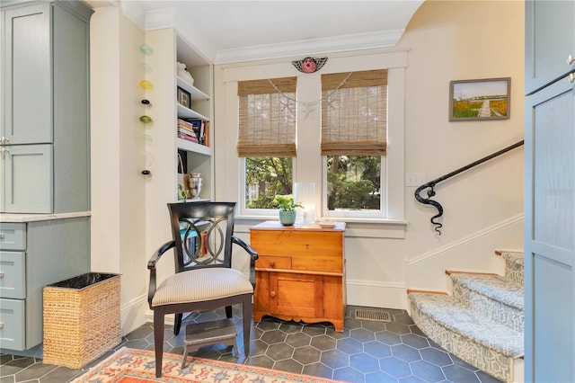 sitting room featuring visible vents, dark tile patterned floors, ornamental molding, baseboards, and stairway
