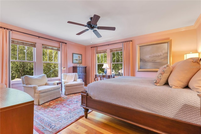 bedroom with wood finished floors, a ceiling fan, ornamental molding, and multiple windows