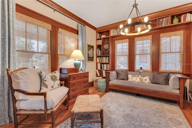 sitting room featuring ornamental molding, an inviting chandelier, built in features, and wood finished floors