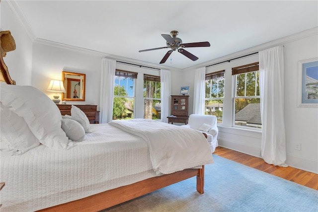 bedroom with wood finished floors, ceiling fan, crown molding, and baseboards