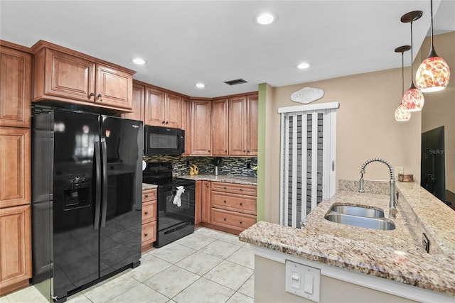 kitchen featuring visible vents, black appliances, light stone counters, a sink, and backsplash