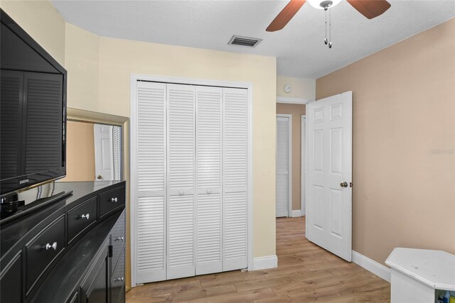 bedroom featuring a closet, light wood-type flooring, baseboards, a ceiling fan, and visible vents