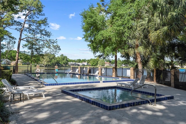 community pool with a patio area, fence, and a hot tub
