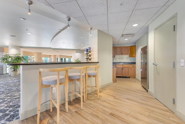 322 E Central Blvd Unit 1008, Orlando, FL 32801 - kitchen featuring dark countertops, a breakfast bar, brown cabinetry, freestanding refrigerator, and light wood-type flooring