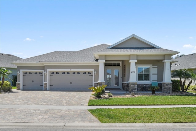 3078 Borassus Dr, New Smyrna Beach, FL 32168 - view of front facade featuring stone siding, a garage, stucco siding, french doors, and decorative driveway