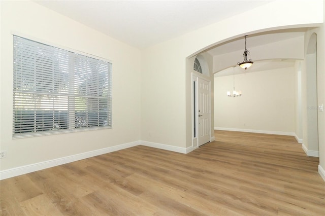 3835 Rock Hill Loop, Apopka, FL 32712 - spare room with arched walkways, baseboards, an inviting chandelier, and light wood-style flooring