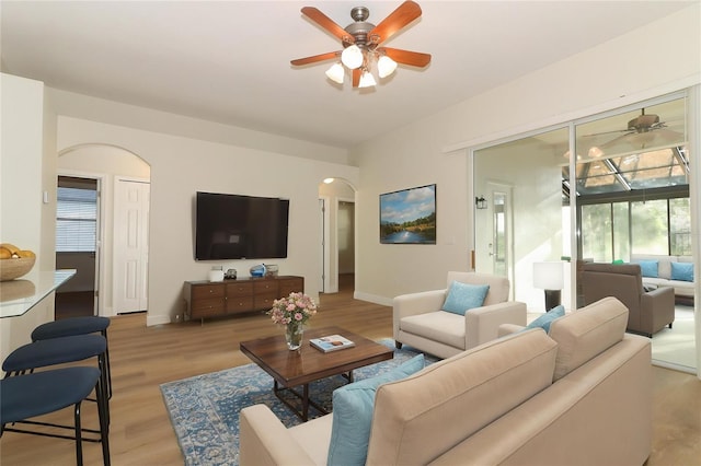 3835 Rock Hill Loop, Apopka, FL 32712 - living area featuring light wood-style flooring, arched walkways, a ceiling fan, and baseboards