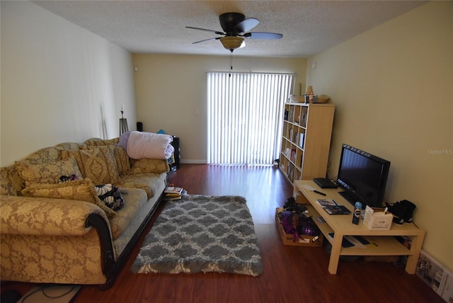 living area featuring a textured ceiling, a ceiling fan, and wood finished floors
