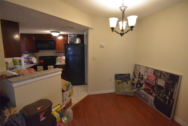 kitchen featuring a chandelier, light countertops, a textured ceiling, light wood finished floors, and black appliances